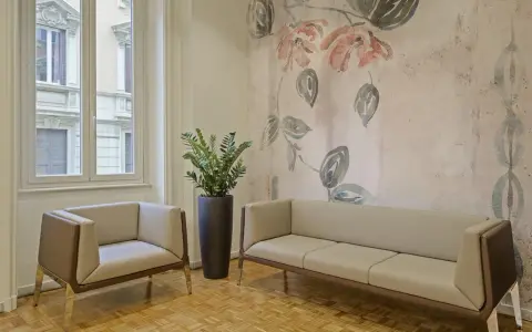 Eleganckie fotele i sofa na tle tapety z motywem kwiatowym. Czy można kleić tapetę na tapetę? Tutaj wygląda to stylowo.