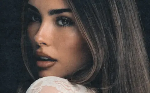 Zbliżenie na twarz Madison Beer, zmysłowe spojrzenie i delikatny uśmiech. Fani Madison Beer Polska czekają na jej powrót.