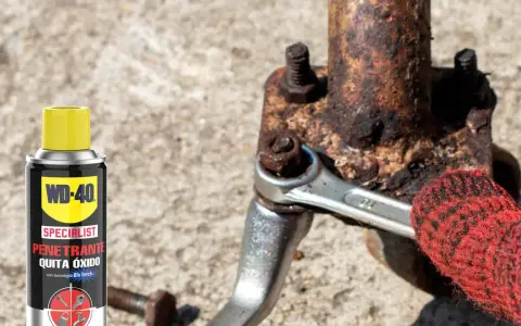 WD-40 ayuda a sacar tornillo roto de pieza oxidada. Llave inglesa y guante rojo en acción.
