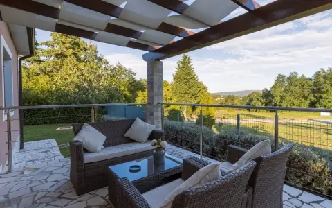 Muebles de mimbre y mesa de cristal en una terraza grande con vistas al campo. Ideas para como decorar una terraza grande con estilo y comodidad.