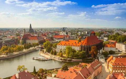 Widok na Ostrów Tumski we Wrocławiu, idealne miejsce na city break z Wrocławia. Rzeka, zabytkowe budynki i błękitne niebo.