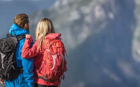 Para jedzie w góry, zastanawiając się, jaki plecak w góry na jeden dzień będzie najlepszy. Ona ma czerwony, on niebieski.