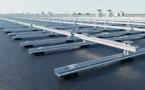Monteringssystem för solpaneler på ett platt tak. Aluminiumprofiler lyfts upp av svarta fötter, redo för installation.