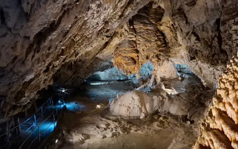 Wnętrze jaskiń w Zakopanem, z naciekami, stalaktytami i stalagmitami, oświetlone niebieskim światłem.