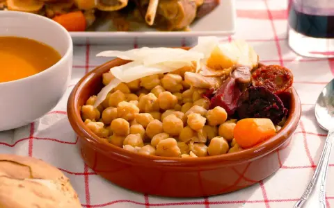 Cocido madrileño con garbanzos, chorizo, morcilla, patata y zanahoria en cuenco de barro.