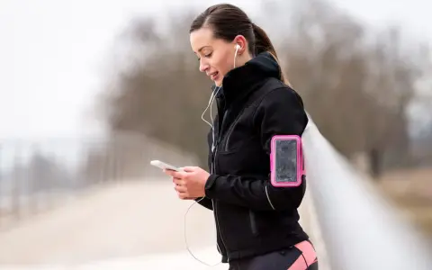 Donna con fascia da braccio rosa per il telefono, ideale per sapere dove mettere il telefono quando si corre.
