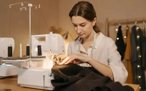 Kobieta szyje na maszynie, przygotowując się do tego, jak wszyć taśmę do firanki.