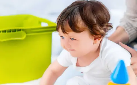 Mały poszukiwacz sensoryczny z zaciekawieniem odkrywa świat, obok niego zielony pojemnik i kolorowe zabawki.
