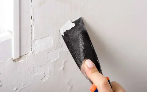 Raspando pintura vieja para preparar la pared. Paso clave para como pintar una pared ya pintada de otro color.