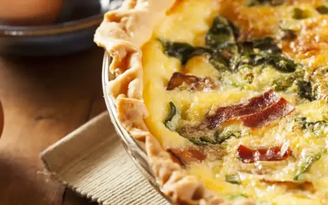 Une délicieuse tarte aux épinards et lardons, dorée et appétissante, prête à être dégustée.