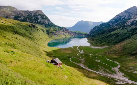 Idyllischer Salzburg See, umgeben von grünen Bergen. Eine Hütte am Hang lädt zum Verweilen ein.