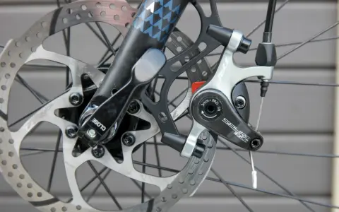Nahaufnahme einer Fahrradscheibenbremse. Die Bremsbeläge sind sichtbar, was einen Hinweis darauf gibt, wann bremsscheiben wechseln.