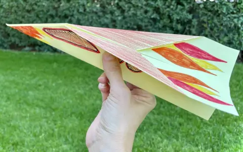 Bunter Papierflieger mit Flammenmuster, bereit zum Abheben. Hier ist die papierflieger anleitung zum ausdrucken.