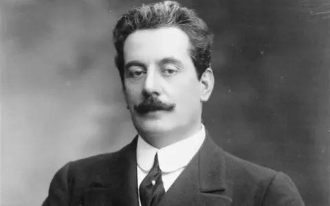 Giacomo Puccini, kompozytor słynnych **puccini opery**, w eleganckim garniturze i z charakterystycznymi wąsami.
