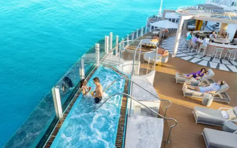 Coppia in jacuzzi su nave da crociera Caraibi, con bar e lettini prendisole. Un sogno di volo e crociera Caraibi.