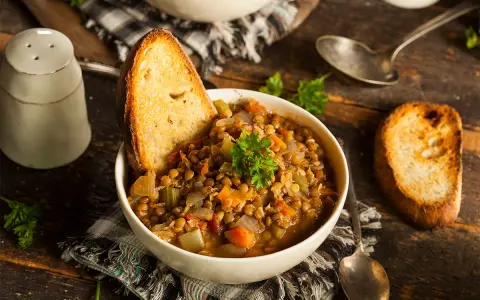 Zuppa di lenticchie ricca e saporita, servita con pane tostato e prezzemolo fresco. Un classico tra le ricette con lenticchie.