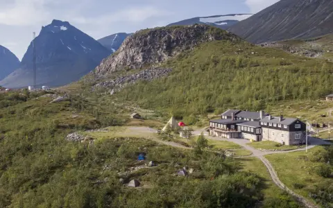 STF Kebnekaise fjällstation med tält och fjäll i bakgrunden. En plats för äventyr och naturupplevelser.