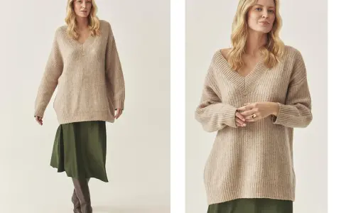 Modelka w beżowym swetrze w stylu oversize i zielonej spódnicy.