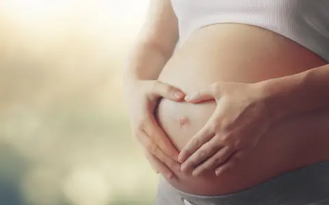 Czekając na dziecko, zastanawiasz się, czy autyzm można wykryć w ciąży? Dłonie tworzą serce na brzuchu.