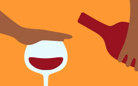 En hand stoppar ett glas rött vin medan en flaska hälls. Kanske en påminnelse om att vara försiktig med alkohol, särskilt om man tar medicin som Diamox.