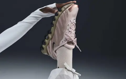 Różowy but Nike na obcasie, trzymany przez dłoń w białej rękawiczce.