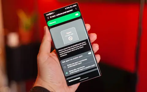 Dłoń trzyma smartfon z włączoną ochroną przed spamem. Ekran pokazuje powiadomienie o potencjalnym spamerze, gdy dzwonią z laboratorium.