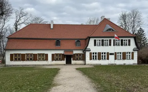 Dworek z czerwonym dachem i białymi ścianami, z polską flagą. Słychać tu echo gwary pomorskiej.