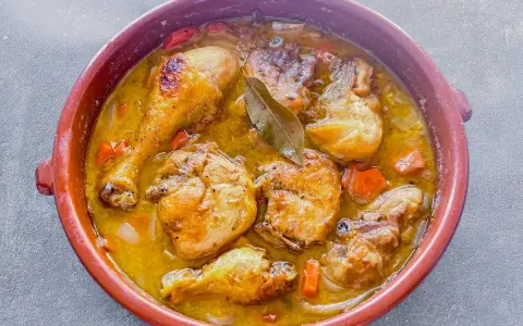 Muslos de pollo en salsa, un plato casero que evoca la receta de la abuela. Jugosos trozos de pollo dorados en una rica salsa con zanahorias y laurel.