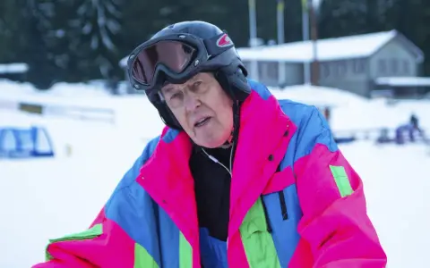 Äldre man i färgglad skidjacka och hjälm, redo för backen. Kanske en veteran från Edsbyn skidor.
