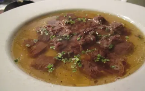 Ein Teller mit Tafelspitz, zartes Rindfleisch in Brühe, garniert mit frischen Kräutern. Ein Klassiker des Tafelspitz Rezepts.