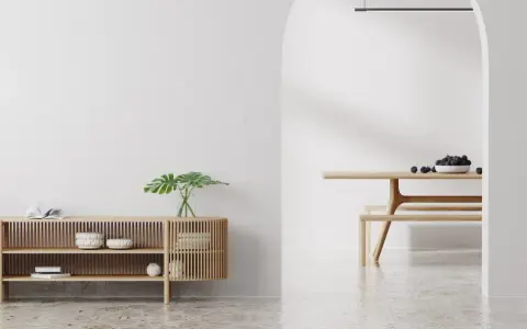Un espacio minimalista con un aparador de madera y un comedor. Las paredes lisas y el suelo pulido crean un ambiente sereno.