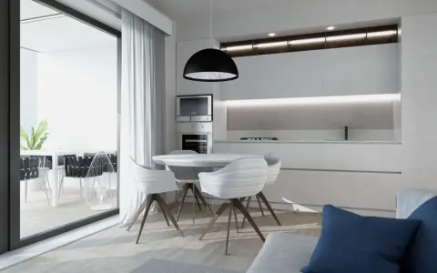 Interni luminosi di una casa di design con cucina moderna, tavolo rotondo e sedie bianche. Si intravede un terrazzo con piante.