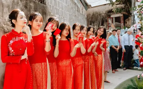 Novias y damas de honor con trajes rojos tradicionales, sosteniendo sobres rojos, celebrando una boda china.