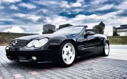Czarny Mercedes SL R230 na parkingu. Nawet klasyki mają swoje **awarie i problemy**, ale ten wciąż wygląda świetnie.