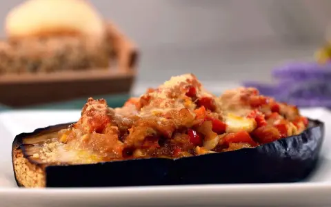 Berenjenas rellenas de atún, gratinadas con queso y trocitos de tomate. Un plato delicioso y fácil de preparar.