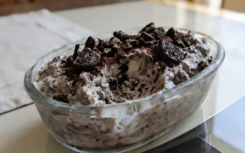 Pyszne lody oreo w szklanej misie, posypane pokruszonymi ciastkami i kakao. Idealne na deser!