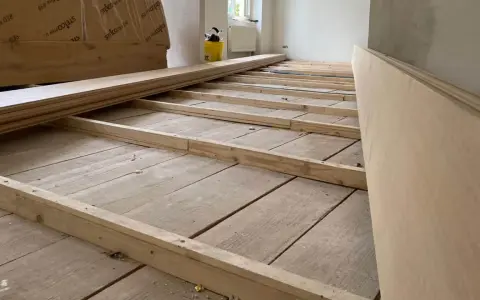 Holzbalken werden auf alten Dielen verlegt, um den Untergrund für einen neuen Dielenboden auszugleichen.