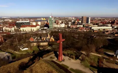 Góra Gradowa z czerwonym monumentem w kształcie krzyża na tle panoramy miasta.