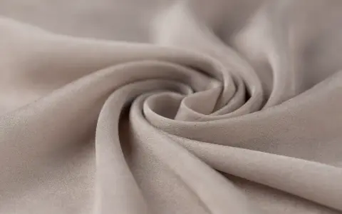 A swirl of soft, beige fabric. This close-up shows the texture and drape of a material, making one wonder, is viscose a good material for flowy garments?