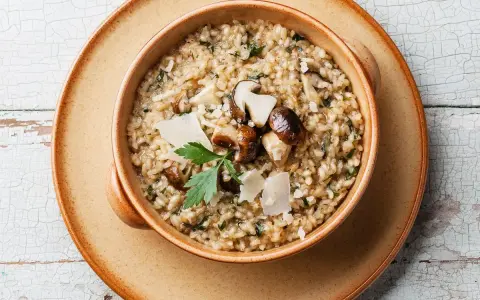 Un cremoso risotto ai funghi, un clásico plato italiano, servido en un cuenco de cerámica.