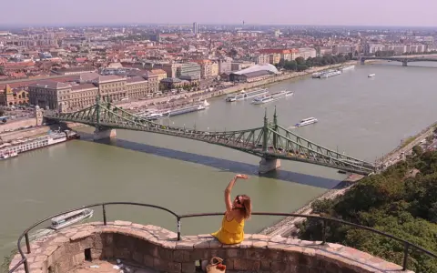 Widok na Dunaj w Budapeszcie z zielonym mostem i kobietą w żółtej sukience.