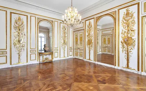 Salón dorado del museo Carnavalet, con suelo de parqué, candelabro de cristal y ornamentación dorada en las paredes.