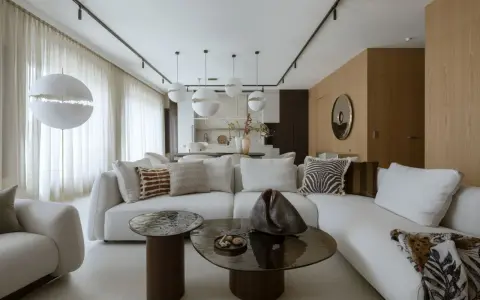 Nowoczesny projekt mieszkania z białą sofą, okrągłymi stolikami i designerskimi lampami.