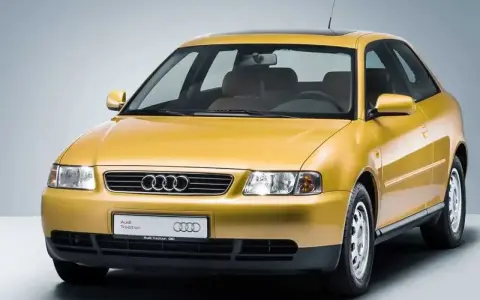 Gelber Audi A3 Baujahr 2000, dreitürig, mit Schiebedach und dem Schriftzug "Audi Tradition".