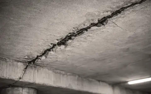 Detalle de grietas en el techo de hormigón, mostrando el acero de refuerzo expuesto. Posibles causas de grietas en el techo.