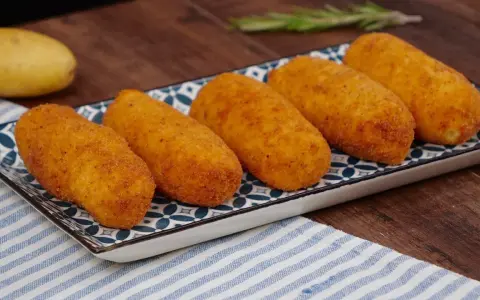 Cinque crocchette di patate dorate e croccanti su un piatto decorato, pronte per essere gustate.