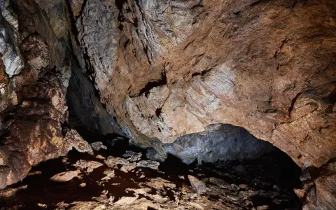 Wnętrze jaskini mylnej, z kamienistym dnem i skalnymi ścianami o rdzawym zabarwieniu, tworzącymi naturalne sklepienie.