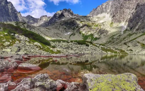 Kamieniste zbocza i skaliste szczyty otaczają spokojną taflę wody w Dolinie Batyżowieckiej.