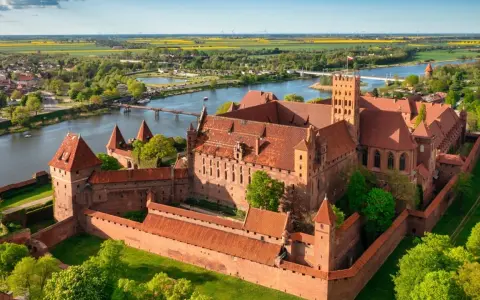 Malbork zamek krzyżacki, potężna twierdza z cegły, góruje nad rzeką Nogat. Otoczony murami, z wieżami i dziedzińcami, zaprasza do odkrywania historii.