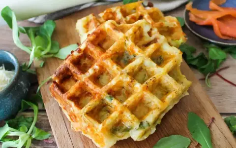 Gaufres salées dorées, garnies de poireaux et fromage, prêtes à être dégustées. Une recette facile pour un repas savoureux.